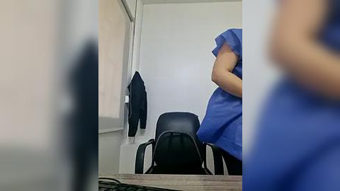 Media: A blurred video of a person in blue scrubs, likely a nurse, holding a patient in a hospital room. The patient's face is blurred, with a black jacket hanging on a door.