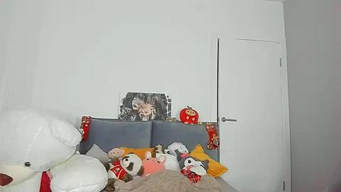 Media: A video of a child's bedroom corner with a white door, a gray headboard, stuffed toys, a small red pumpkin, and a framed picture of a child with a red scarf.