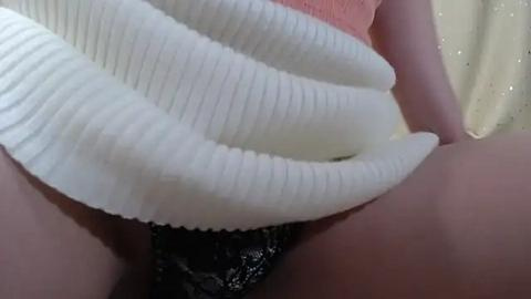 Media: Video of a close-up view of a person's hand holding a large, white, ribbed, textured object, likely a hose, against a pale yellow background. The person's fingers are visible, indicating a soft, possibly delicate texture of the object.