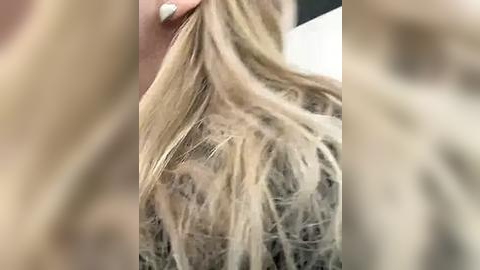 Media: A close-up video of a blonde woman's shoulder-length hair, showing strands tangled and matted, with a light-colored background. Her skin tone is light, and her nails are painted white.