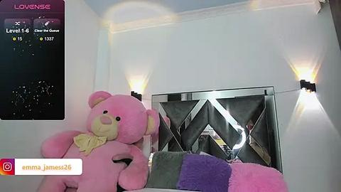 Media: A video of a pink teddy bear on a bed, with a diamond-patterned wall and modern lighting. The image is taken from a low angle, showing a social media post with James25's username.