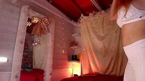 Media: Video of a cozy, festive bedroom with white walls, a red curtain, fairy lights, a white mirror, and a white bed, creating a warm, inviting ambiance.