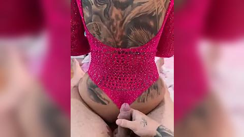 Media: A video of a tattooed woman in a red, fishnet bodysuit, seated on a man's lap, with a visible erect penis.