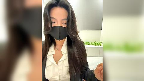 Media: A video shows a masked, dark-haired woman in a white blouse and black blazer, holding a piece of paper in a modern, bright office.