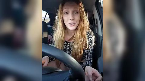 Media: A video of a woman with long, wet blonde hair, wearing a black and white patterned top, driving a car with blurred figures in the background.