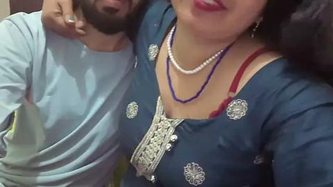 Media: A video shows a man with a beard and mustache in a light blue shirt, hugging a woman in a blue, embroidered kurta with white and red designs, and pearl necklaces.