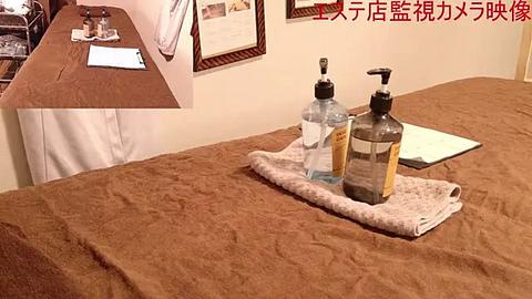 Media: Video of a neatly made bed with a beige bedspread and a beige tray holding a water bottle, hand sanitizer, and a white cloth. A framed certificate hangs on the cream-colored wall in the background.