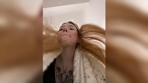 Media: Video of a woman with long blonde hair, her hair caught in a fan, creating a whimsical, surreal effect.