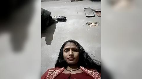 Media: Video of a woman with long black hair, wearing a red saree, sitting in a car with a large pothole on the road.