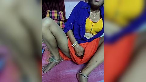 Media: Video of an older woman with short hair, wearing a blue jacket over a yellow bra and red shorts, sitting on a pink carpet, legs spread, surrounded by colorful, blurry objects.