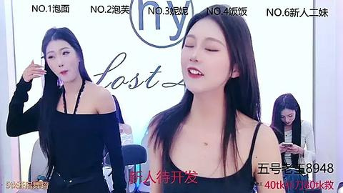 Media: Video of a slender Asian woman with long black hair, wearing a black off-shoulder top, smiling with eyes closed, in a bright, white room.