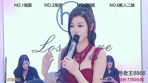 Media: Video of a fair-skinned East Asian woman with long dark hair, wearing a red lace dress, speaking into a microphone at a press conference. Background features Chinese text and multiple people in black clothing.