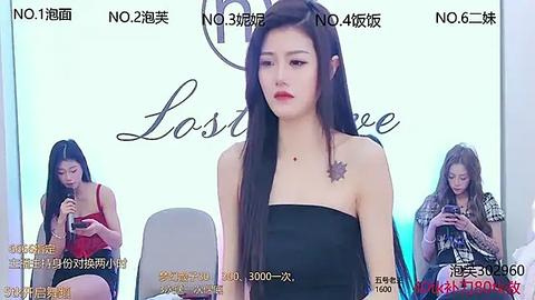 Media: Video of a young Asian woman with long black hair, wearing a black strapless dress, standing in front of a backdrop with Chinese text.