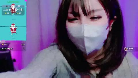 Media: A video of an Asian woman with long black hair, wearing a white mask, and a light-colored shirt, taken indoors with a purple backdrop.