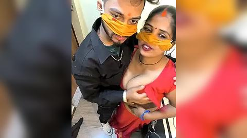 Media: Video of two young Indian women wearing orange masks, one in a red saree, the other in a black jacket, taken from a high angle, showing a playful interaction.