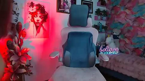 Media: A video of a modern gaming chair with a blue cushion, set against a vibrant, colorful room with pink walls, a unicorn plush toy, and a Marilyn Monroe poster.