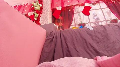 Media: Video of a cozy, festive room with a pink couch, red and white holiday decor, and a window showcasing a snowy landscape.