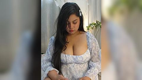 Media: A video of a curvy Latina woman with long black hair, wearing a light blue floral dress, sitting outside in natural daylight, looking down.