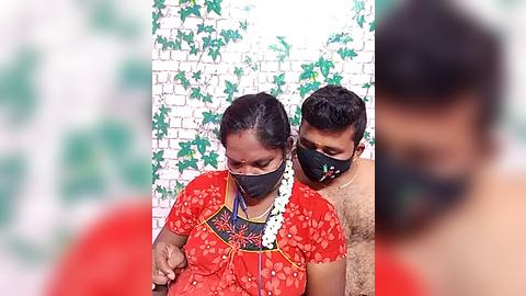 Media: Video of a woman and child wearing face masks, standing in front of a white brick wall with green ivy, both smiling.