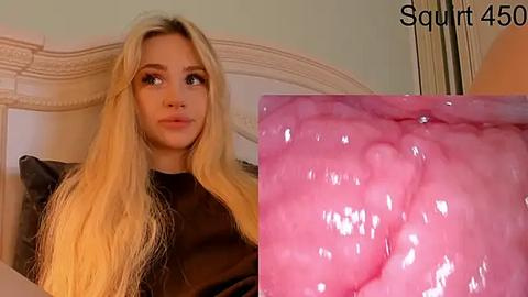 Media: Video of a blonde woman with long hair, dressed in black, sitting on a white bed. Close-up of her pink, inflamed throat.