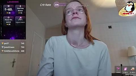 Media: Video of a young, pale-skinned woman with red hair, wearing glasses and a light blue shirt, captured on a livestream titled \"Grit Rate: 100\" in a dimly-lit room.