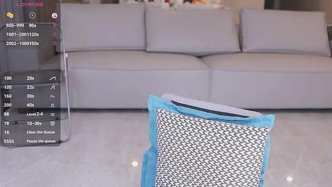 Media: Video of a modern living room with a light grey sofa, a blue cat scratching post, and a smart device displaying a virtual cat.