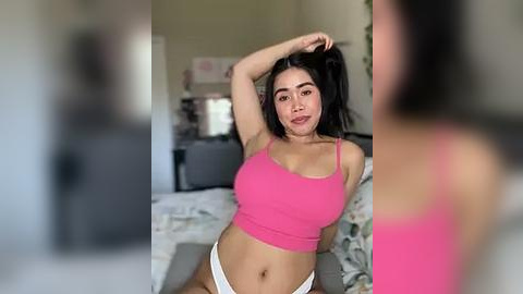 Media: Video of a young woman with medium skin tone, long black hair, wearing a pink crop top and white panties, posing seductively in a bedroom with blurred background.