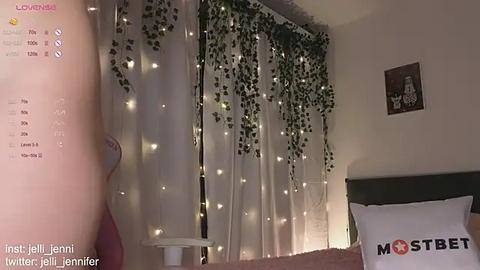 Media: Video of a cozy bedroom with fairy lights, green ivy, white curtains, and a \"MOSTBET\" pillow.