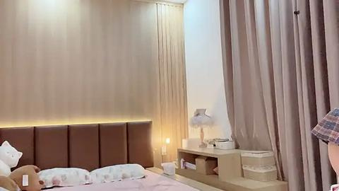 Media: Video of a modern bedroom with a brown leather headboard, beige walls, beige curtains, and a minimalist design featuring a white nightstand and a decorative lamp.