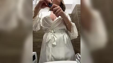 Media: A video of a woman in a white robe, brushing her teeth in a modern bathroom with beige tiles and a white sink.