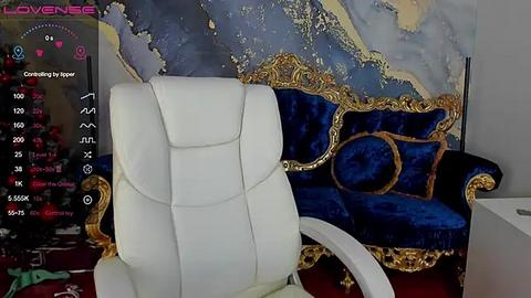 Media: Video of a luxurious living room with a white leather office chair facing a gold-framed, deep blue velvet sofa with ornate patterns, against a marble-patterned wall.