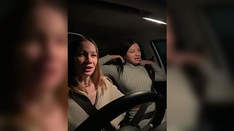 Media: Video of two young women in a car at night. One is driving with a concerned expression, while the other, in a grey sweater, leans back, looking tired.