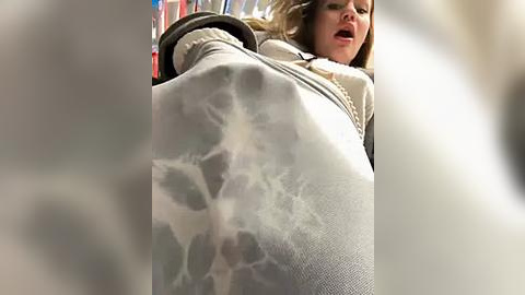 Media: A video of a young woman with long brown hair, wearing a beige sweater and gray leggings, appears to be in distress, her mouth open, and her eyes closed. Her legs are prominently featured, partially obscured by a foggy, translucent substance.