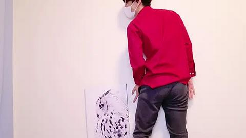 Media: Video of a man in a red shirt and dark jeans, wearing a white mask, painting a large black-and-white leopard illustration on a white wall.