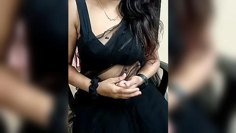 Media: Video of a woman with medium skin tone, wearing a black sleeveless dress, holding a cigarette. She has long, wavy dark hair, and a black wristwatch. Background is blurred.