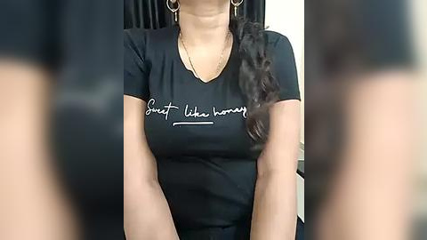 Media: Video of a woman in a black t-shirt with the phrase \"Sweat Like a Pig\" in white cursive. She wears hoop earrings and has a dark-haired cat resting on her shoulder.