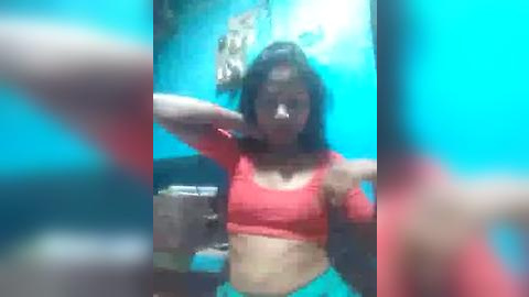 Media: A blurry video of a young woman with medium skin tone, dark hair, and a red crop top, captured in a bathroom with teal walls.