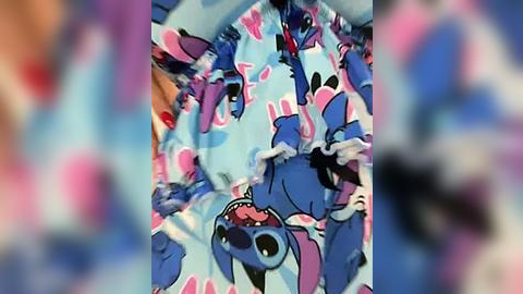 Media: A colorful, blurry video featuring a blue and pink Stitch-themed blanket, with the animated character's playful expressions and floppy ears prominently displayed.