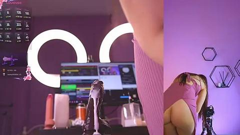 Media: Video of a woman in a pink dress with a large dildo, standing in a purple room with a neon sign, a computer monitor, and various sex toys.