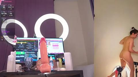 Media: Video of a nude woman with a large, pink dildo, standing in a dimly lit room with a bright, circular vanity mirror and a computer screen displaying chat messages.