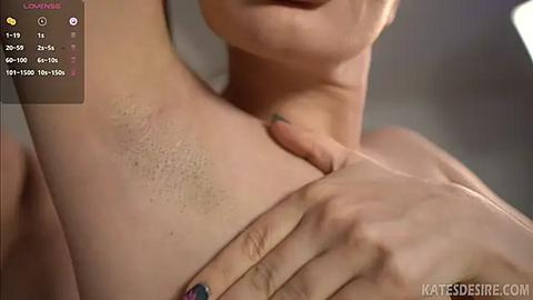 Media: Video of a close-up of a woman's upper body, showing her fair skin, smooth chest, and hand with blue-painted nails gently touching her breast. The background is blurred, with a watermark \"KATESEDESIRE.COM.\