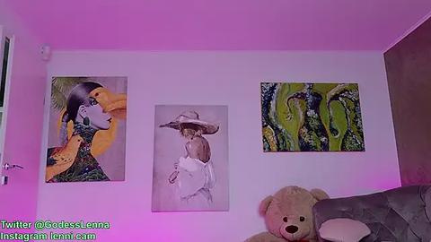 Media: Video of a bedroom wall featuring three framed paintings in pastel hues, a beige teddy bear, and a pinkish-purple glow.