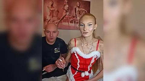 Media: A video features a bald, tattooed man in a black shirt and a blonde woman in a red, Santa-themed outfit with white fur trim, both smiling.