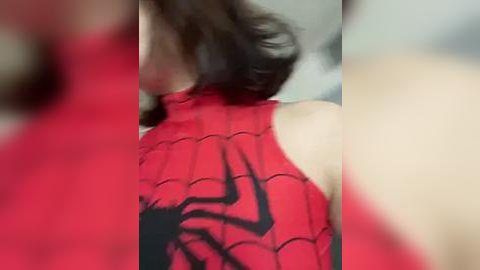 Media: Video of a woman in a red, sleeveless Spider-Man costume with black webbing, featuring a blurry background.