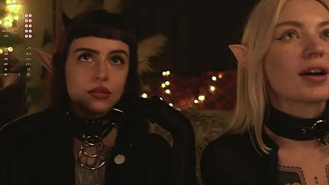 Media: A video features two cosplayers dressed as elves, one with a dark bob and the other with blonde hair, in a dimly lit room with string lights and a fireplace.