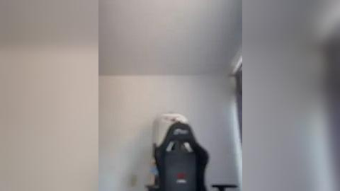 Media: A blurred video of a person sitting on a gaming chair, facing a wall with a white shirt and a gray hoodie, hands covering their face.