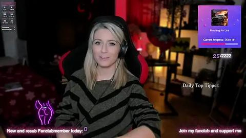 Media: Video of a woman with blonde hair, wearing headphones, seated in a dark room with gaming setup. Text overlays include \"New and Improved\" and \"Join my Twitch and support me.\