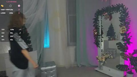 Media: Video of a festive room with a woman in a black dress, a mirror adorned with greenery, and purple and blue lighting.