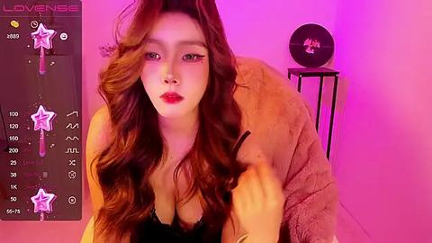 Media: Video of a young East Asian woman with wavy, reddish-brown hair, wearing a black lace bra, posing seductively in a pink-lit room, with a \"Love Sex\" sign on the left.