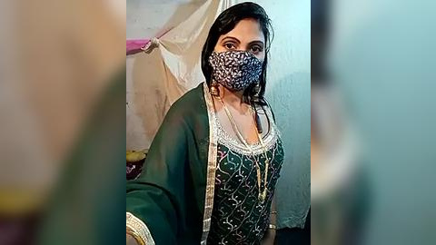 Media: A video of a woman wearing a leopard-print mask, green dupatta, and traditional green outfit, standing indoors against a white wall.